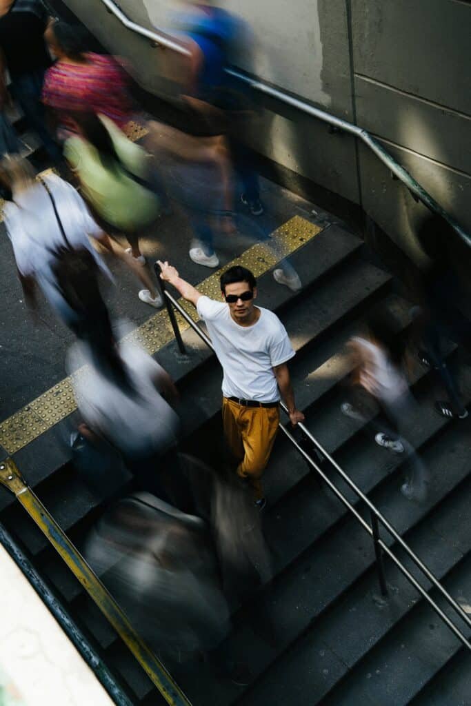 Busy flight of stairs with most people blurring past - only one person in focus.